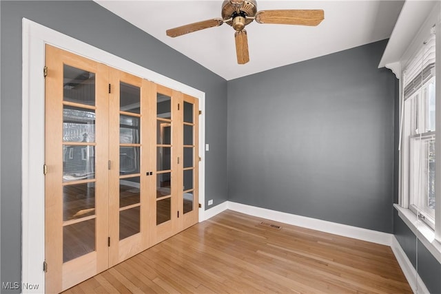 unfurnished room featuring visible vents, wood finished floors, baseboards, ceiling fan, and french doors