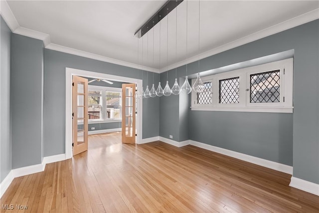 unfurnished dining area with french doors, a ceiling fan, hardwood / wood-style flooring, baseboards, and ornamental molding