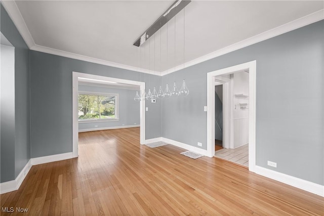 spare room with light wood-style floors, baseboards, crown molding, and visible vents