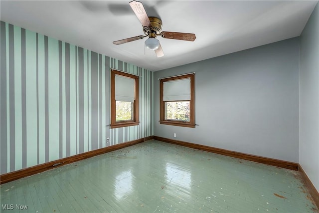 unfurnished room featuring a ceiling fan, baseboards, and wood finished floors