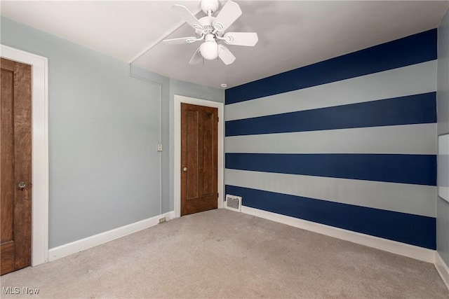 carpeted spare room with a ceiling fan, baseboards, and visible vents