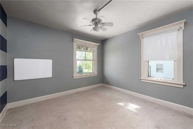 empty room featuring a ceiling fan, baseboards, and carpet
