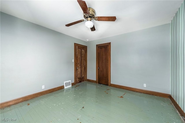 empty room featuring baseboards, a ceiling fan, wood finished floors, and visible vents