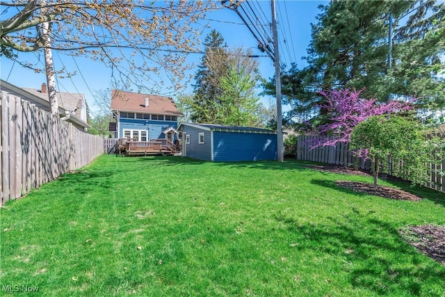 view of yard featuring an outdoor structure, a wooden deck, and a fenced backyard