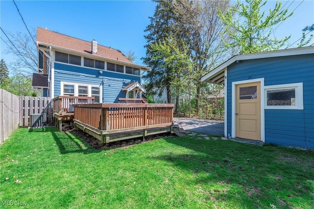 back of property featuring a fenced backyard, a yard, central AC, and a deck