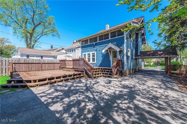 back of house featuring a chimney, fence, and a deck