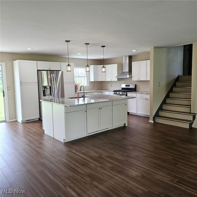 kitchen with wall chimney range hood, recessed lighting, a sink, and stainless steel appliances