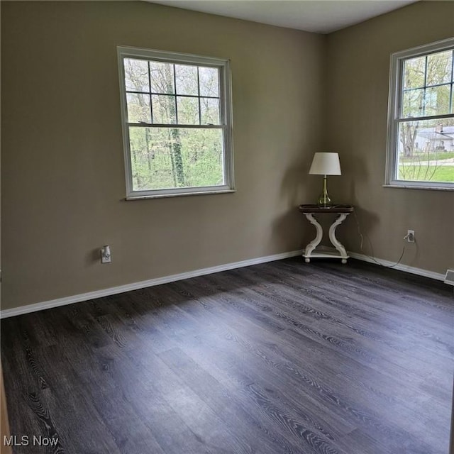 spare room featuring dark wood-style flooring and baseboards