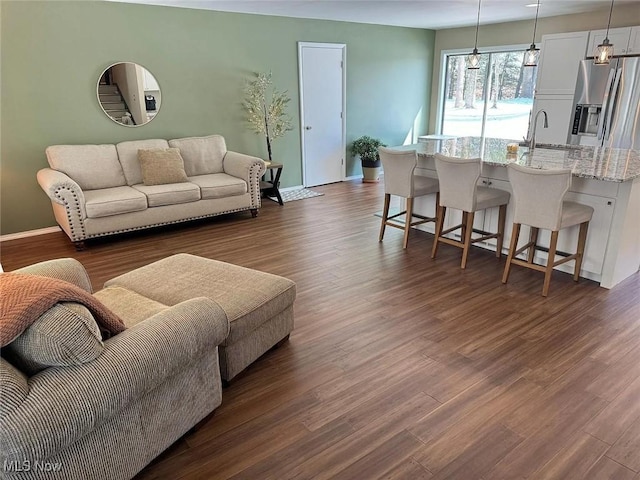 living area with baseboards and dark wood finished floors
