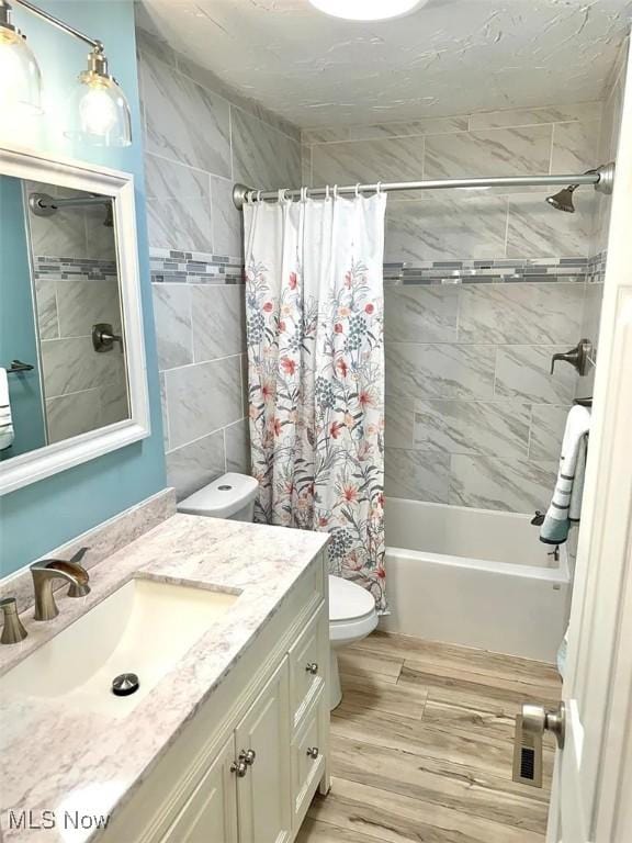 bathroom with shower / bath combo with shower curtain, wood finished floors, toilet, and vanity