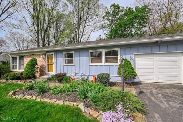 single story home with roof with shingles, board and batten siding, an attached garage, and driveway