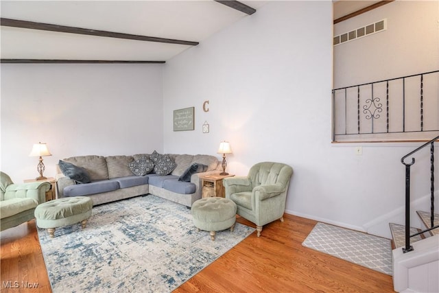 living area with visible vents, baseboards, wood finished floors, and beam ceiling