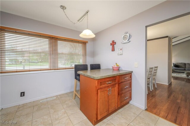 kitchen featuring baseboards, decorative light fixtures, brown cabinets, and visible vents