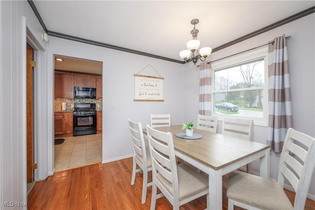 dining space with crown molding, baseboards, an inviting chandelier, and light wood-style flooring
