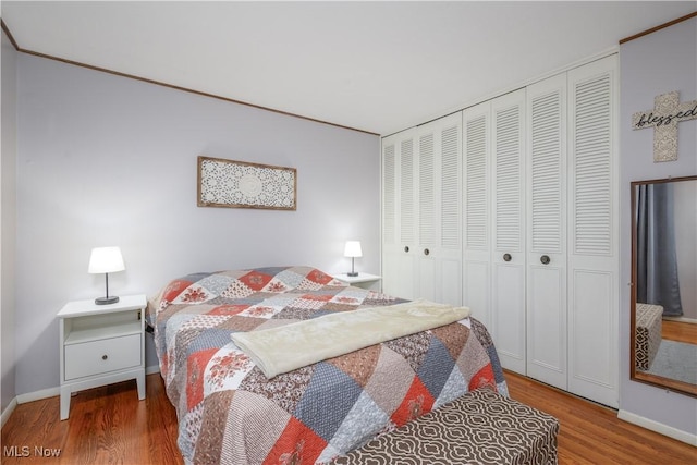 bedroom featuring baseboards, wood finished floors, and a closet