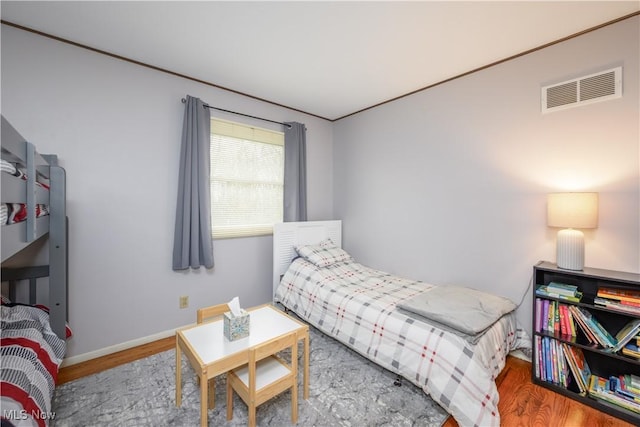 bedroom featuring visible vents, baseboards, and wood finished floors