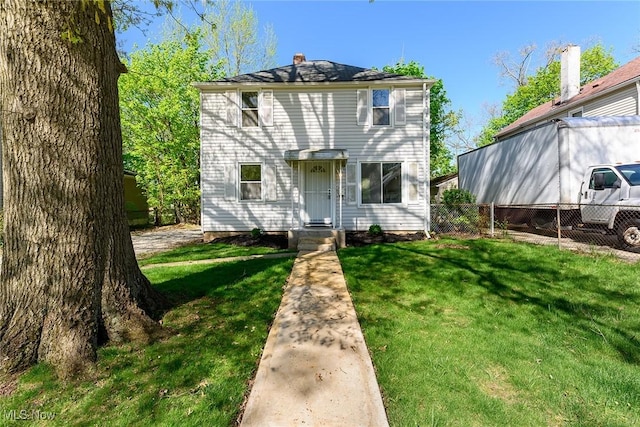 traditional style home featuring a front lawn, fence, and a chimney