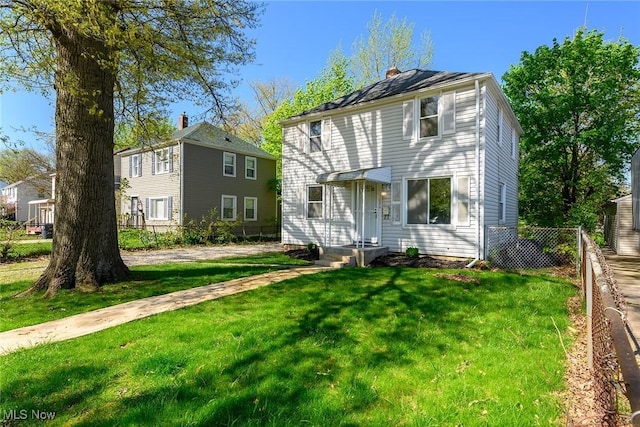 traditional style home with fence, a chimney, and a front lawn