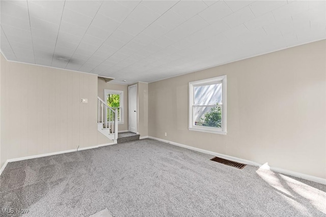 carpeted spare room with baseboards, stairs, and visible vents