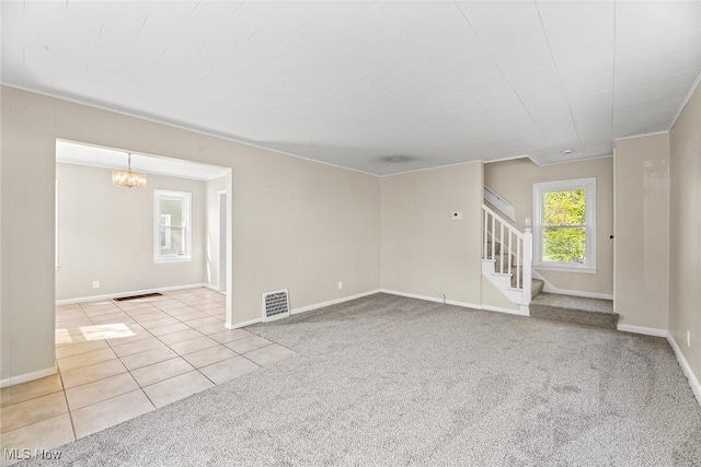 carpeted spare room featuring a notable chandelier, tile patterned flooring, stairs, baseboards, and visible vents