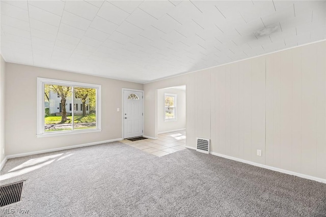 unfurnished living room with baseboards, carpet, and visible vents