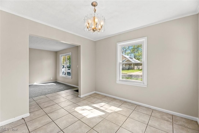 unfurnished room with crown molding, light tile patterned flooring, baseboards, and an inviting chandelier