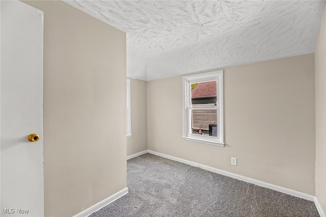 empty room with baseboards, a textured ceiling, and carpet