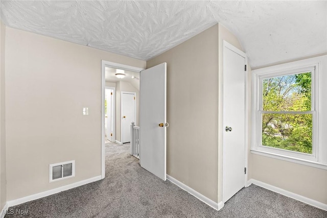 hall with baseboards, visible vents, lofted ceiling, and carpet