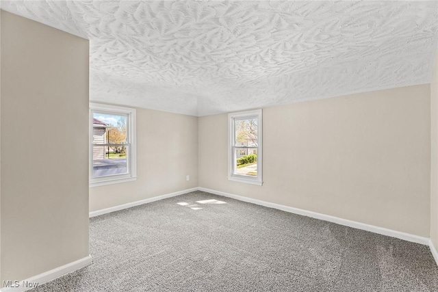 carpeted empty room featuring baseboards and a textured ceiling