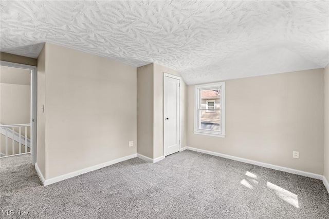 carpeted empty room with baseboards and a textured ceiling
