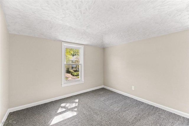 carpeted spare room featuring a textured ceiling and baseboards