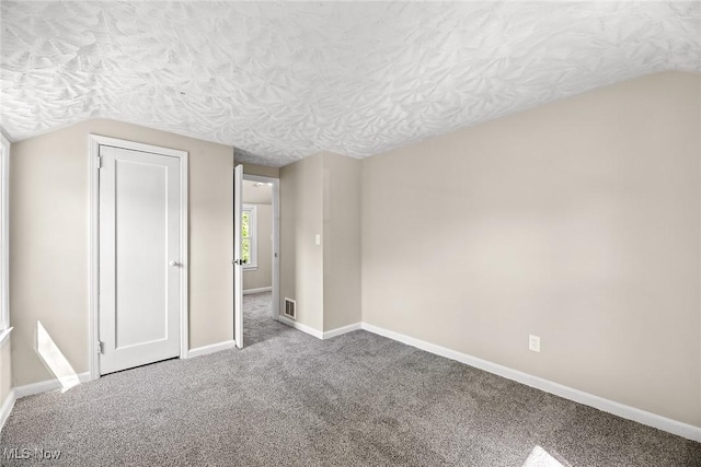 unfurnished bedroom with carpet flooring, baseboards, vaulted ceiling, and visible vents