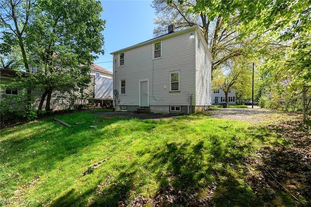 rear view of house with a yard, a chimney, and entry steps
