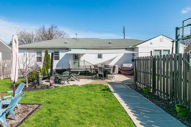 back of property with a patio, a shingled roof, fence, and a yard
