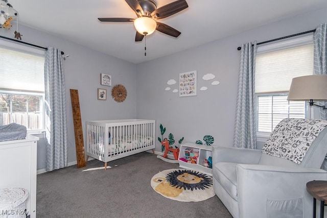 bedroom featuring a crib, baseboards, a ceiling fan, and carpet floors