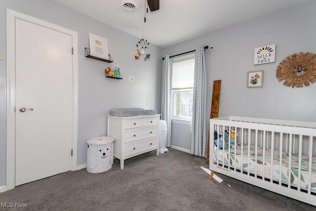 carpeted bedroom with a nursery area, baseboards, a ceiling fan, and visible vents