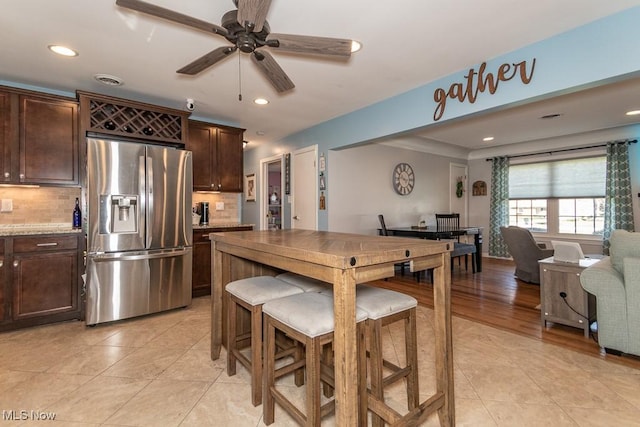 kitchen featuring tasteful backsplash, dark brown cabinets, open floor plan, stainless steel fridge, and recessed lighting