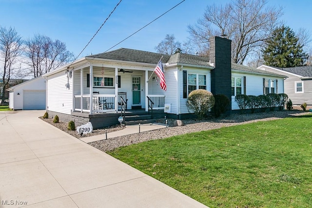 view of front of home with a garage, a front lawn, covered porch, a chimney, and an outbuilding