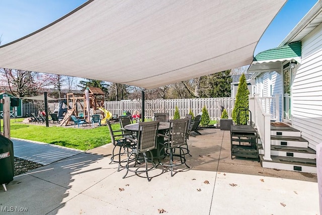 view of patio / terrace featuring a playground, outdoor dining area, and a fenced backyard