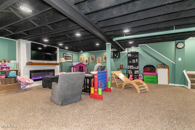 playroom with baseboards, a glass covered fireplace, and carpet