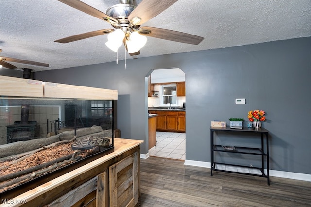 326 N Lyman St, Wadsworth, OH 44281 - interior space featuring a sink, brown cabinetry, a textured ceiling, ceiling fan, and a wood stove