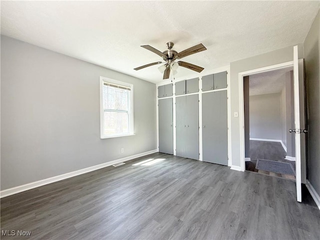 unfurnished bedroom with a ceiling fan, baseboards, dark wood finished floors, and a closet