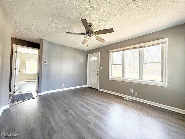 interior space featuring a textured ceiling, dark wood finished floors, a ceiling fan, baseboards, and visible vents