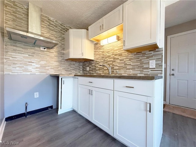kitchen featuring tasteful backsplash, white cabinets, wall chimney exhaust hood, and wood finished floors