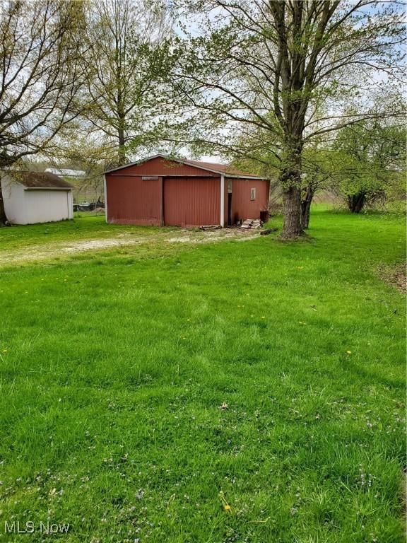 view of yard with a detached garage, an outbuilding, and an outdoor structure