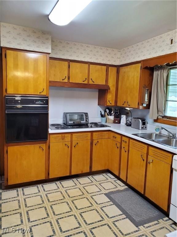kitchen with light floors, light countertops, a sink, and black oven