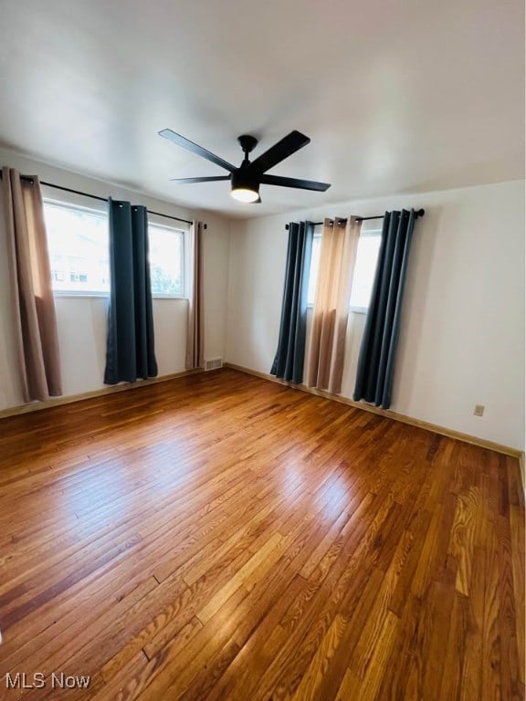 unfurnished room with a ceiling fan, visible vents, and wood finished floors