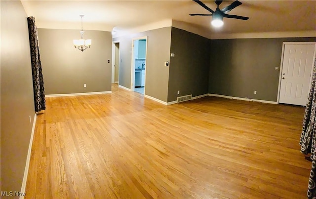 spare room featuring visible vents, light wood-style floors, ceiling fan with notable chandelier, and baseboards