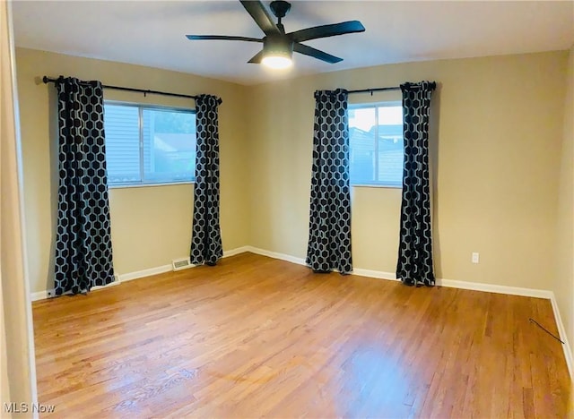 spare room with a ceiling fan, baseboards, visible vents, and wood finished floors
