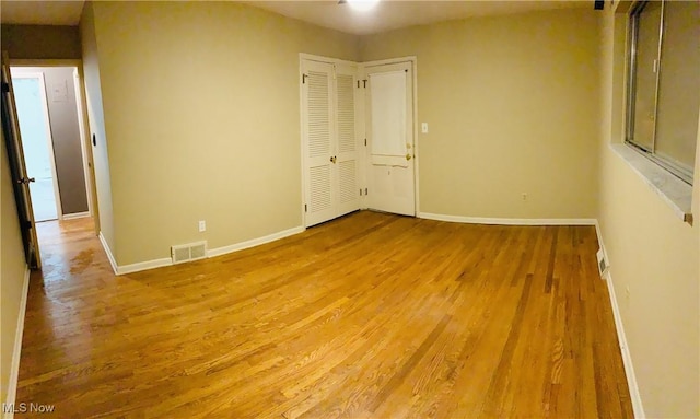 unfurnished room featuring visible vents, baseboards, and wood finished floors